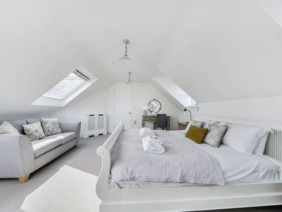 A bedroom with a bed and seating area at Vosporth Villa in Crantock