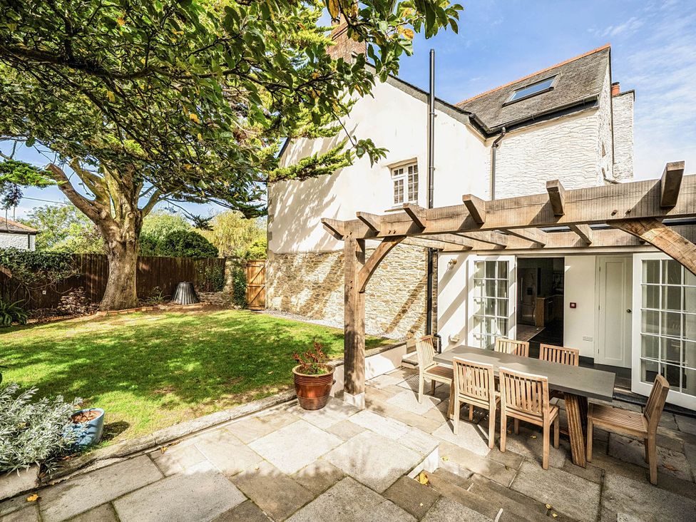 A garden with a table and chairs under a pergola at Vosporth Villa in Crantock