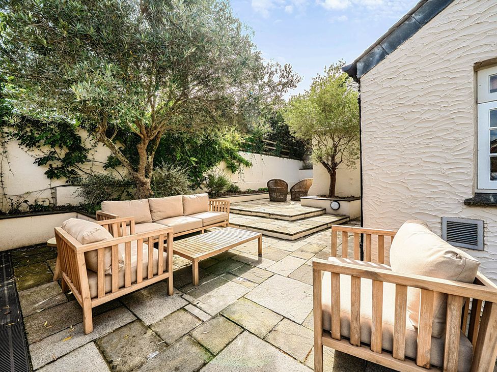 A garden with outdoor seating and trees at Vosporth Villa in Crantock
