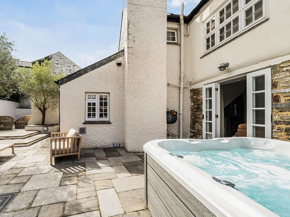 An outdoor area with a hot tub and seating at Vosporth Villa Crantock