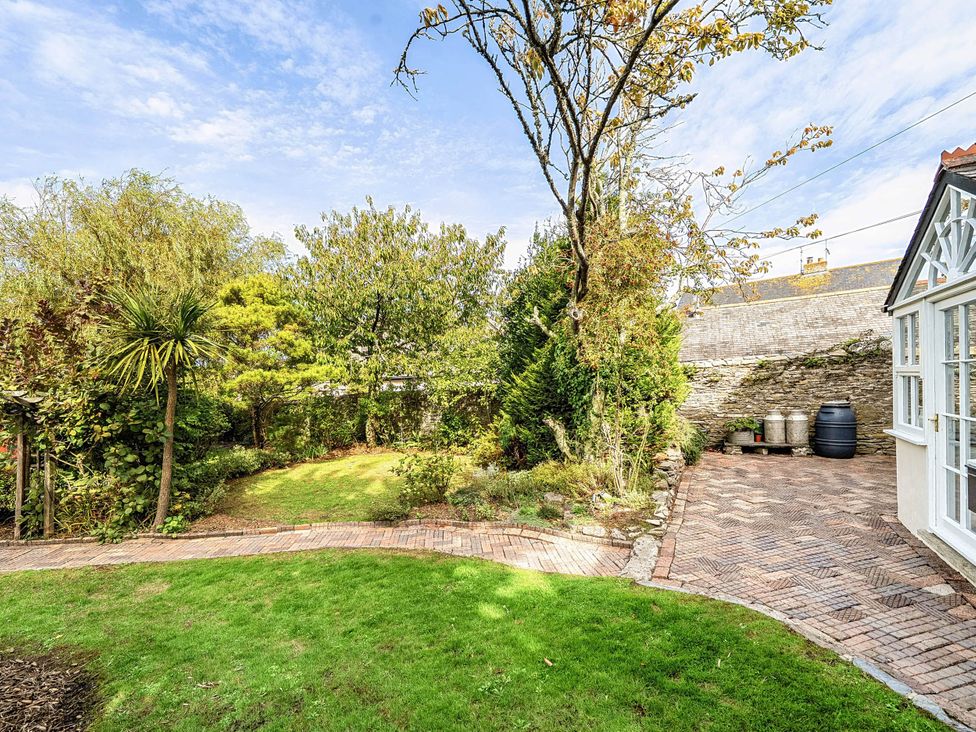 A garden with trees and a brick pathway at Vosporth Villa Crantock