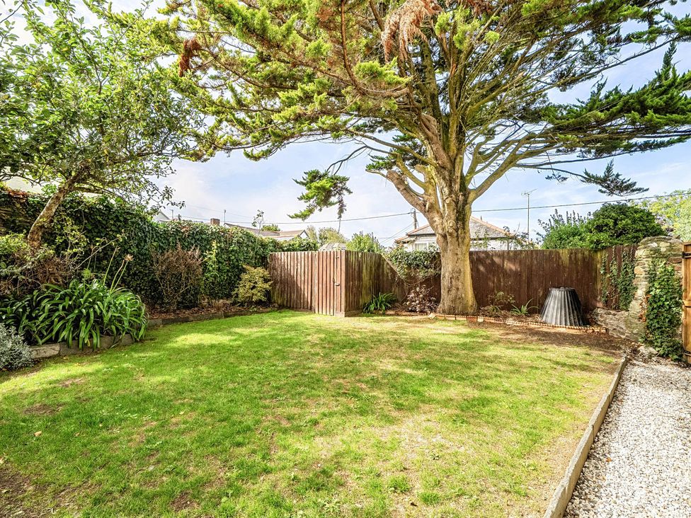 A garden with a tree and fence at Vosporth Villa in Crantock