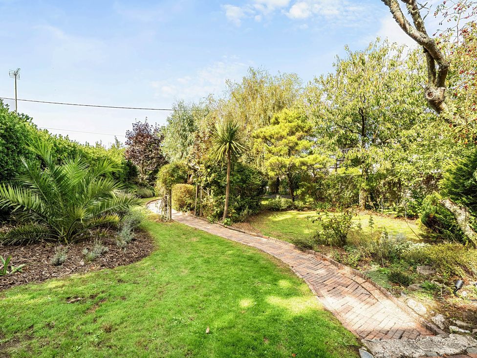 A garden with a pathway and trees at Vosporth Villa in Crantock