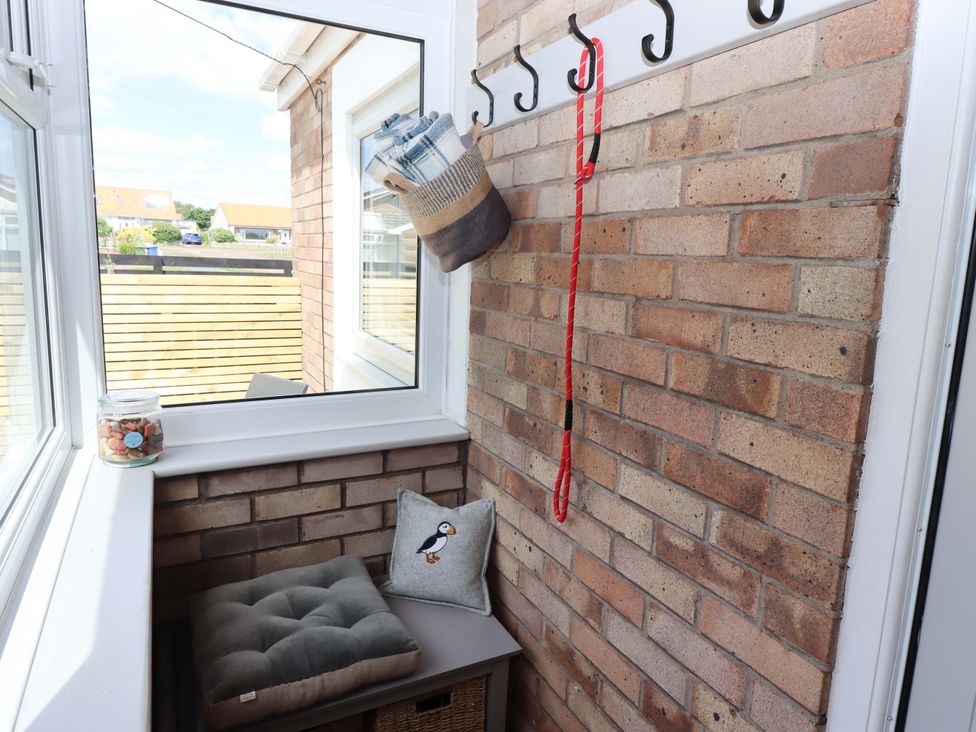 A conservatory with a window, cushion, and hooks at North Sands in Beadnell