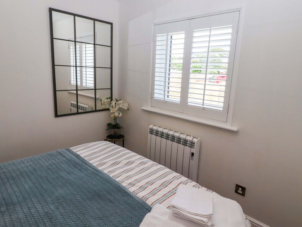 A bedroom with a bed and mirror at North Sands Beadnell