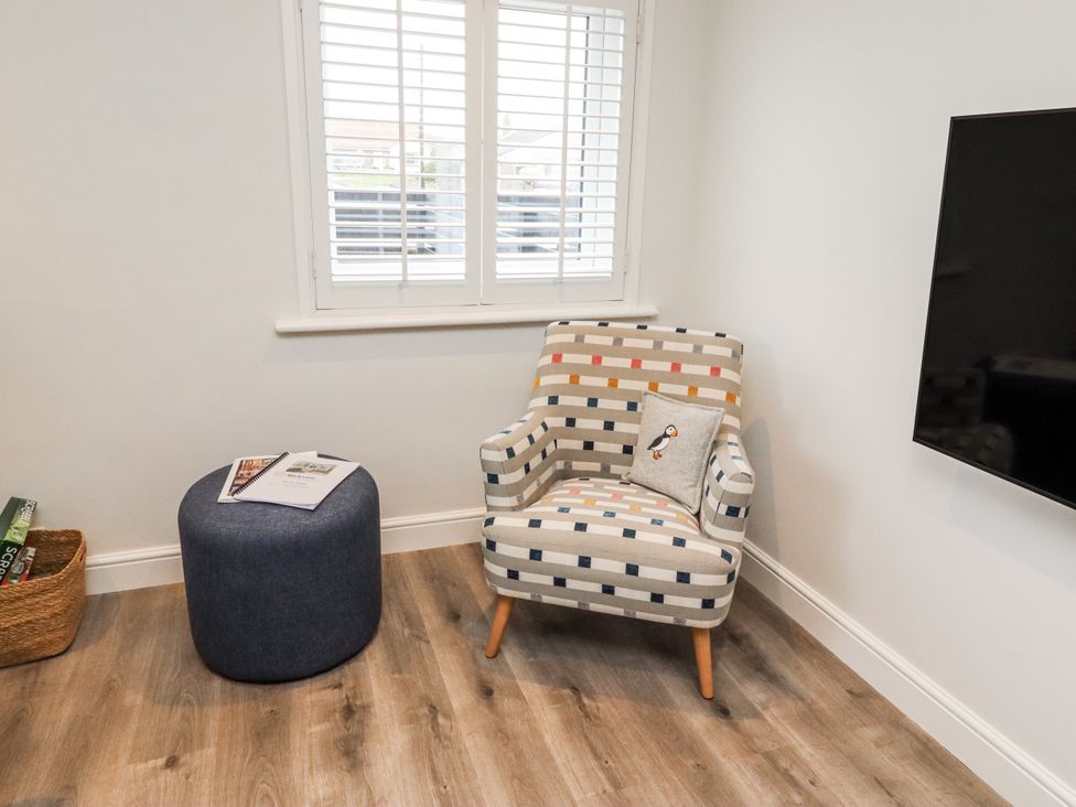 A living room with an armchair and ottoman at North Sands in Beadnell