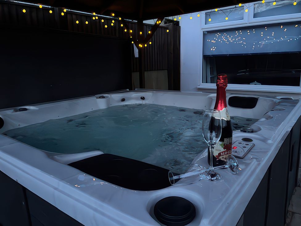 A hot tub with sparkling wine and glasses at Marine House Pevensey Bay