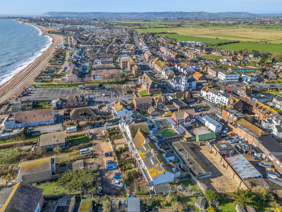An aerial view of a coastal town with houses and a beach at Marine House Pevensey Bay