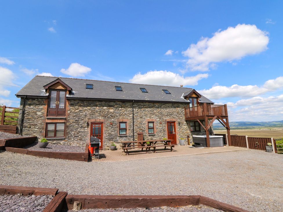 An outdoor area with a stone house and seating at Llwyngwinau Isaf Barn Tynreithyn near Tregaron