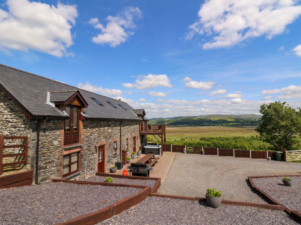 An outdoor view of a house with decking and gravel area at Llwyngwinau Isaf Barn in Tynreithyn near Tregaron