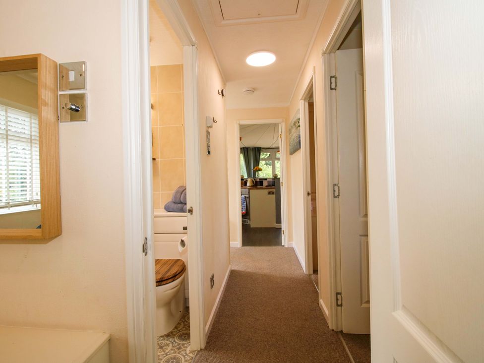 A hallway with a mirror and door leading to other rooms at Dunromin in Montgomery