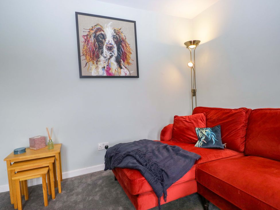 A living room with a red sofa and artwork at Dakota in Boot