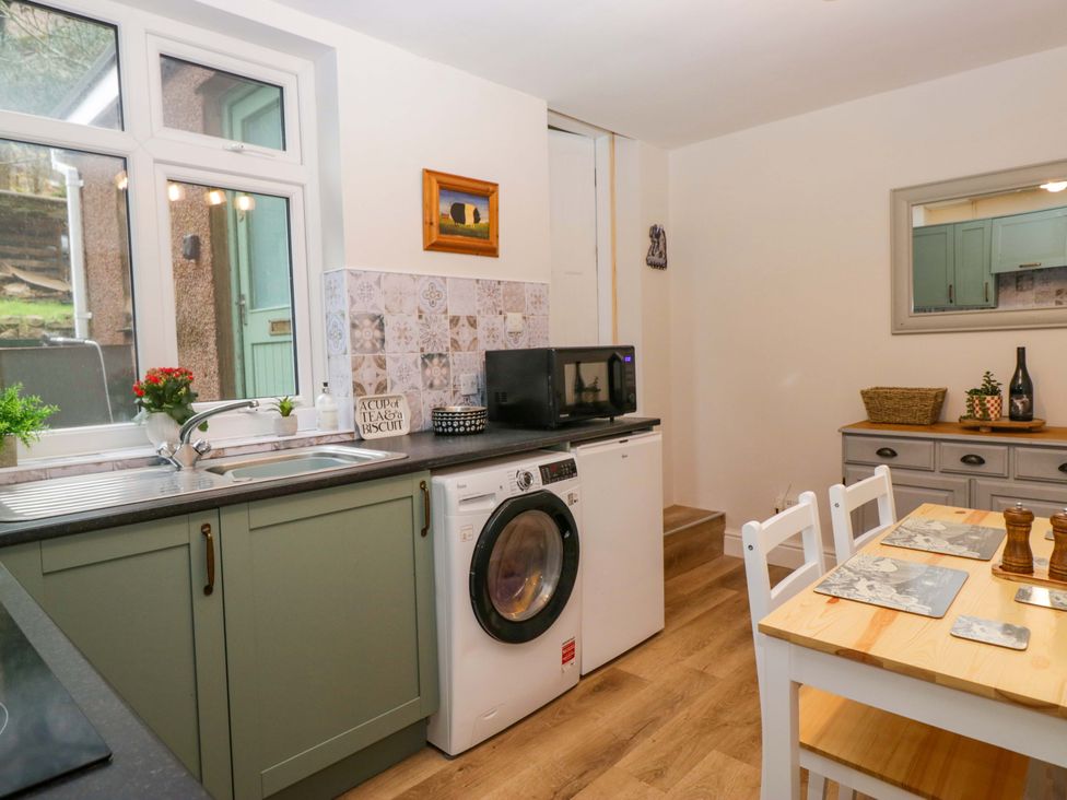 A kitchen with a washing machine and dining table at Dakota in Boot