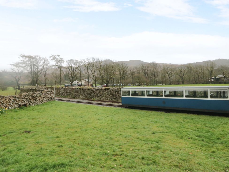 A train on railway tracks with trees and stone wall at Dakota in Boot