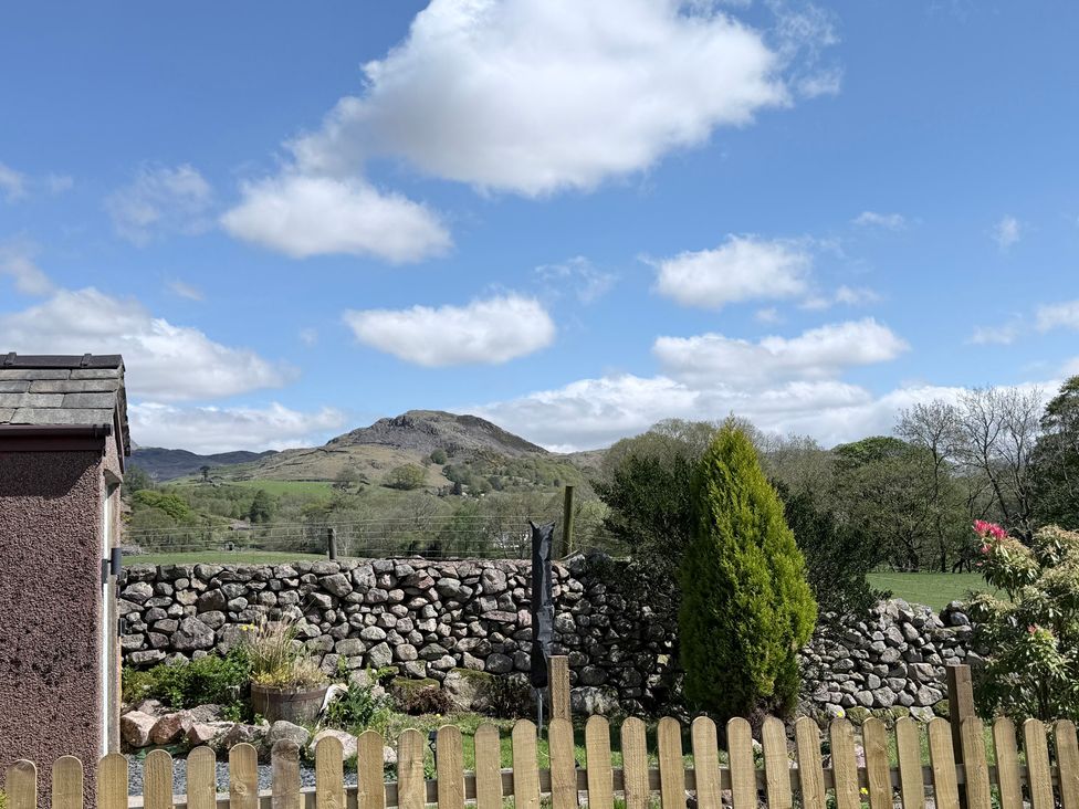 A view of a house and stone wall with mountains and trees at Dakota near Boot