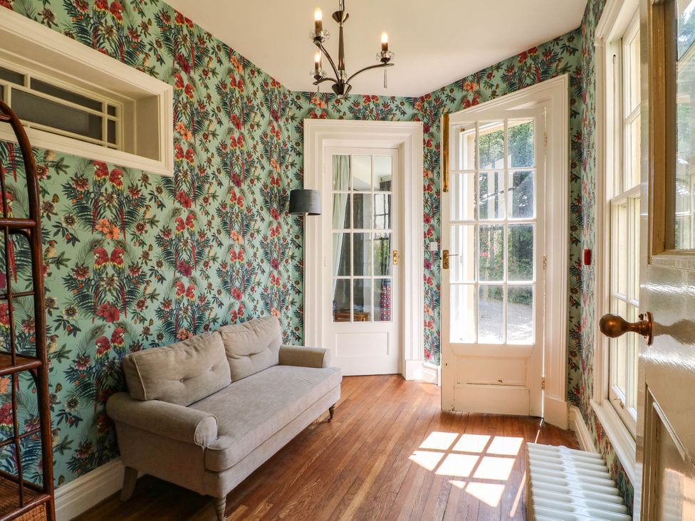 A sunroom with a sofa and doors at Bardon Hill Manor in Coalville