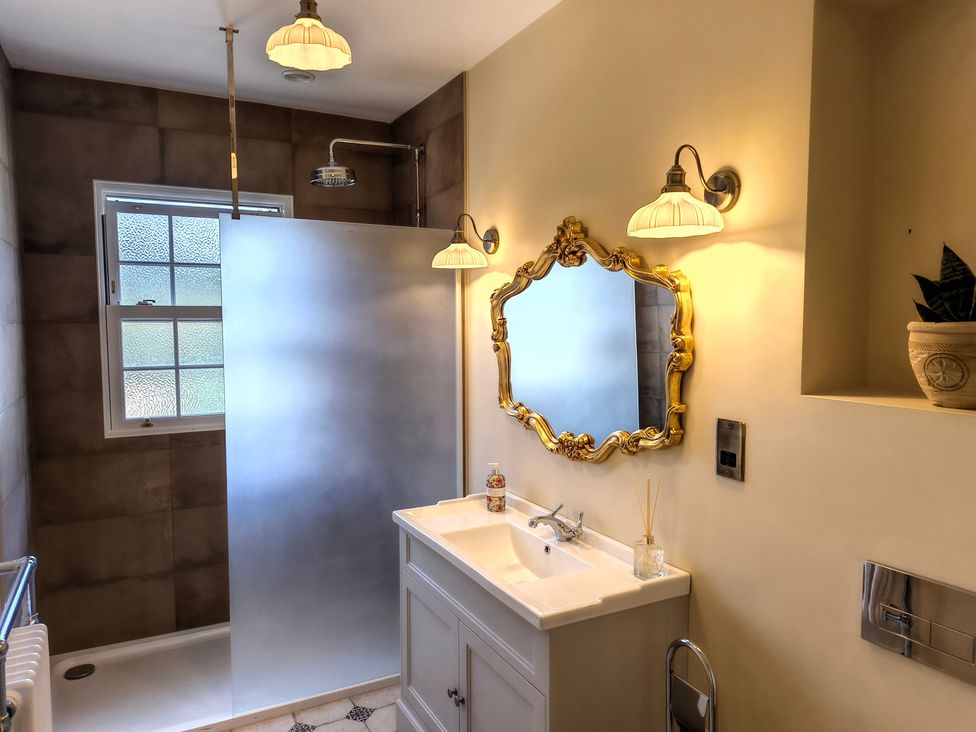 A bathroom with a shower, sink, and mirror at Bardon Hill Manor near Coalville