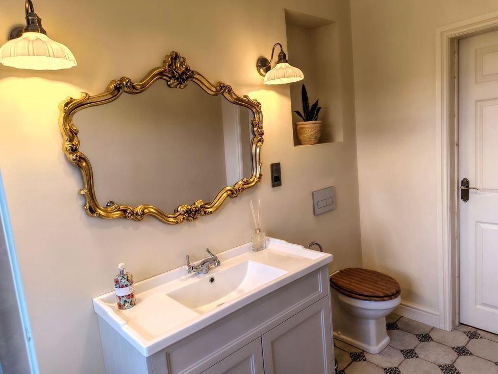 A bathroom with a sink, mirror, and toilet at Bardon Hill Manor near Coalville