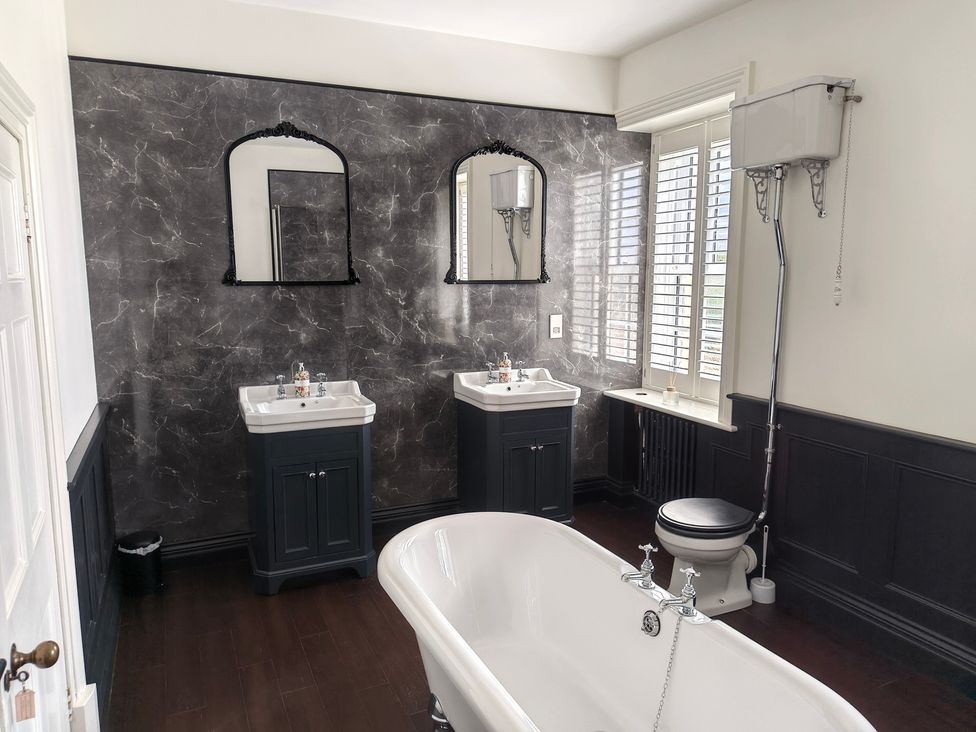 A bathroom with a bathtub, sinks, and a toilet at Bardon Hill Manor near Coalville