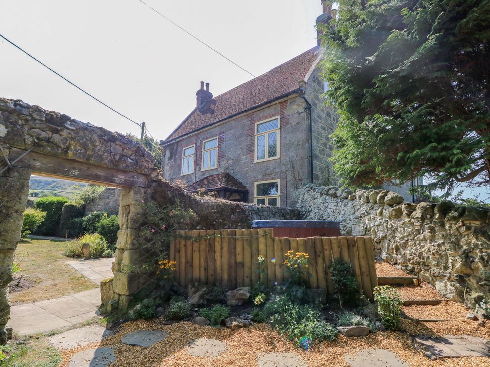 A garden with a house and hot tub at Glebe Garth in Chale near Niton