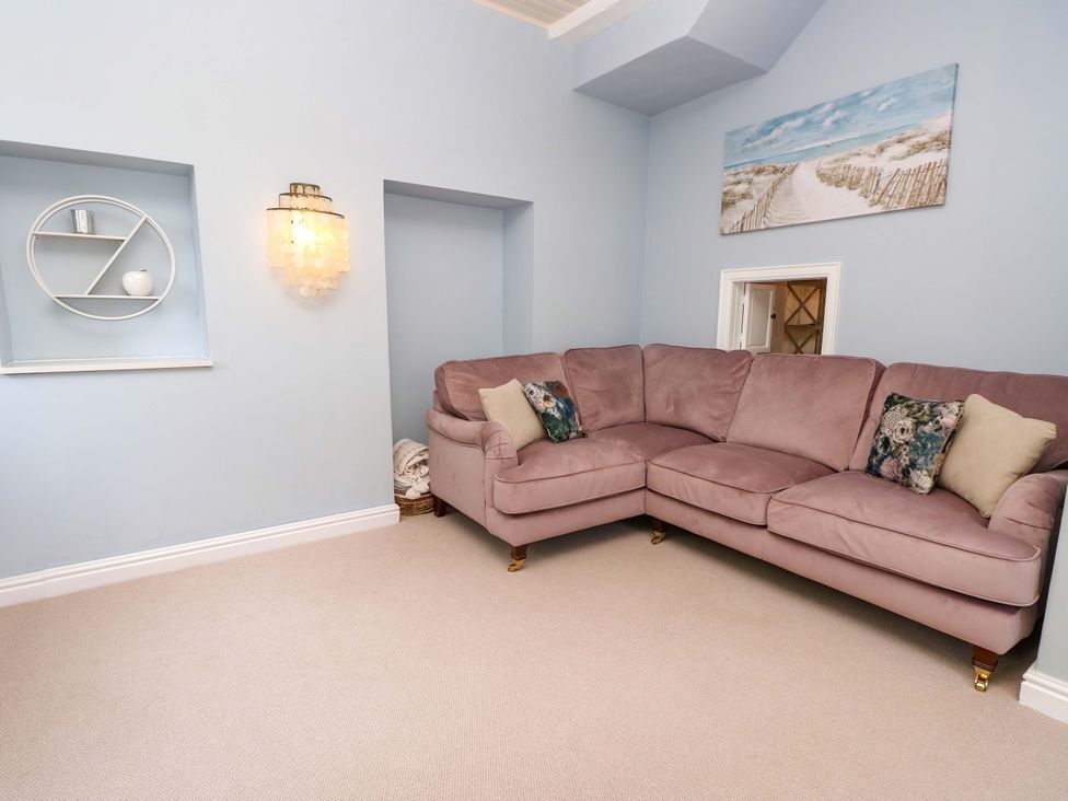 A living room with a sectional sofa and wall shelf at Glebe Garth in Chale near Niton