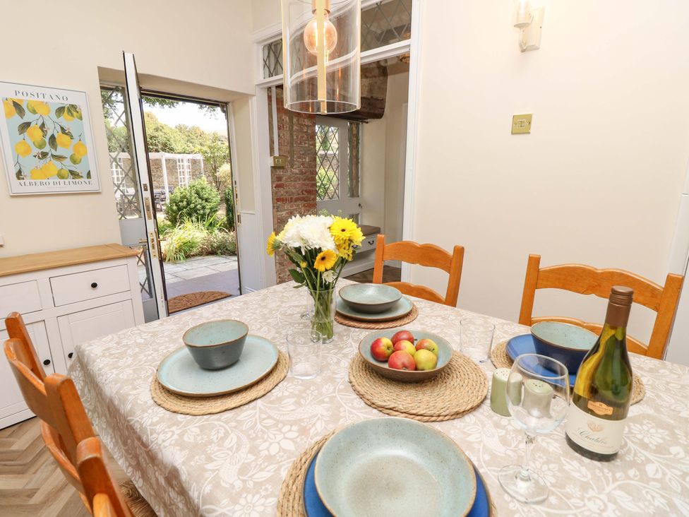 A dining room with a table set and a view of the garden at Glebe Garth in Chale near Niton