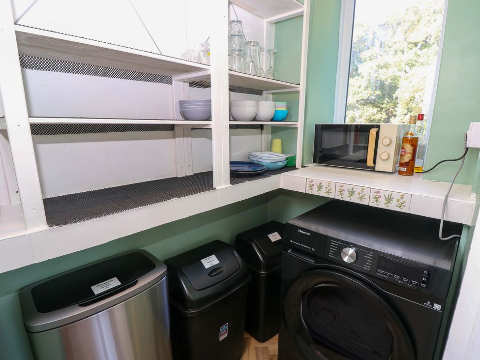 A laundry room with a washing machine and shelves at Glebe Garth in Chale near Niton