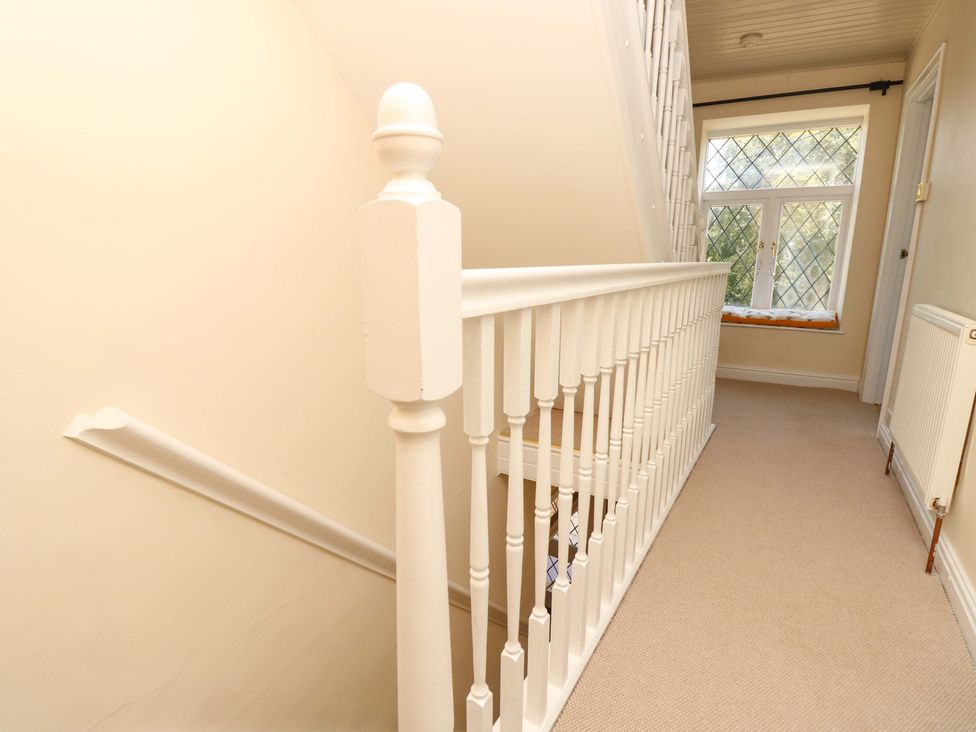 A staircase with a handrail and window in the hallway at Glebe Garth Chale near Niton