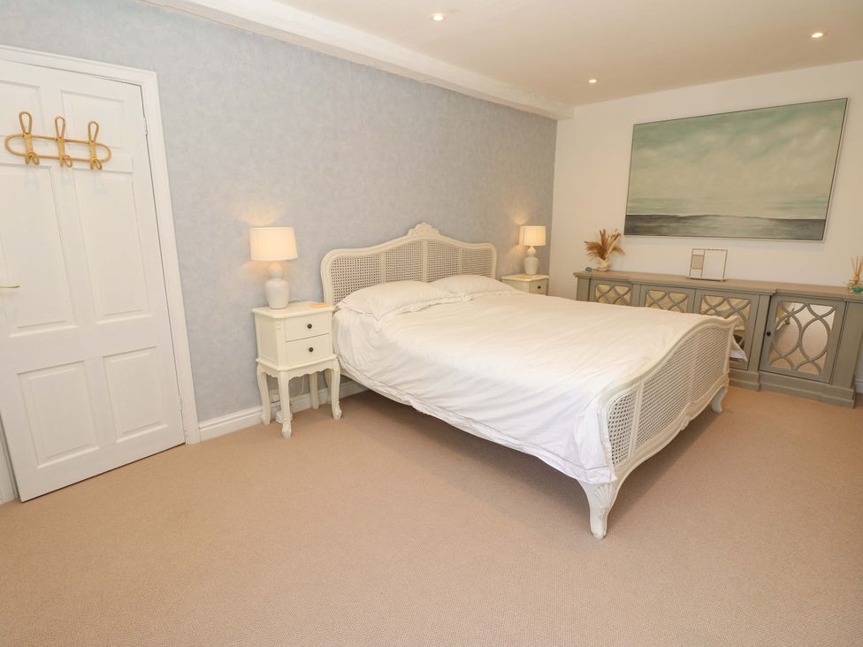 A bedroom with a bed, bedside table, lamp and chest of drawers at Glebe Garth in Chale near Niton