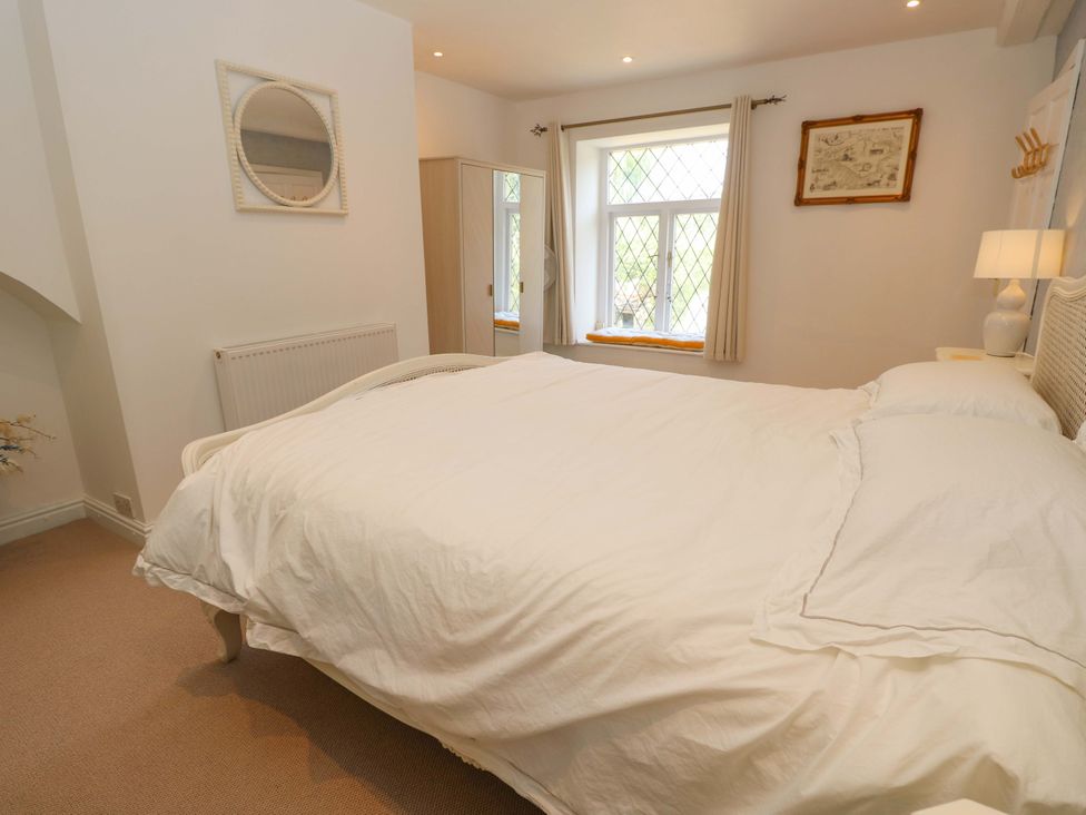 A bedroom with a bed and mirror at Glebe Garth Chale near Niton