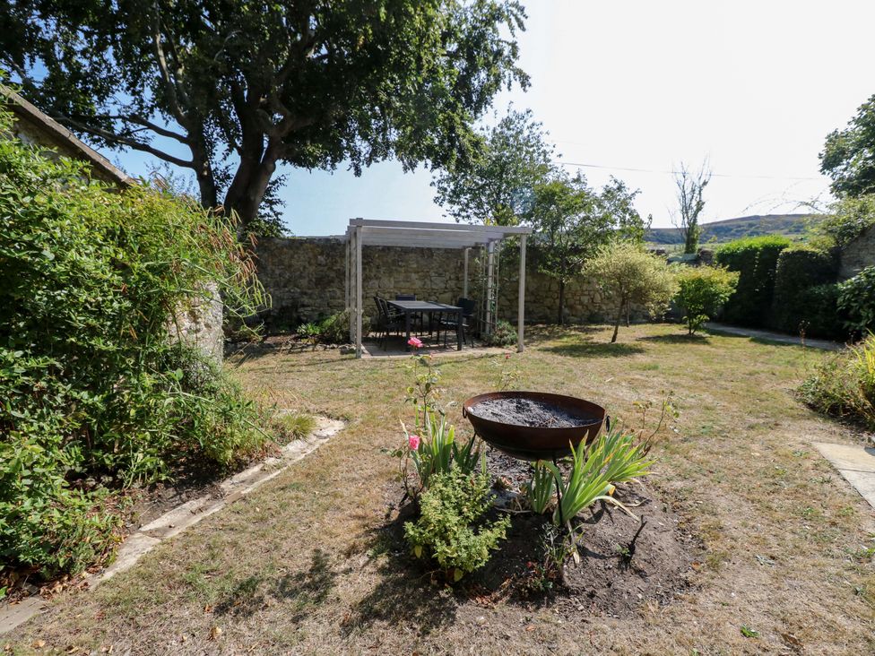 A garden with a table and chairs near a fire pit at Glebe Garth in Chale near Niton