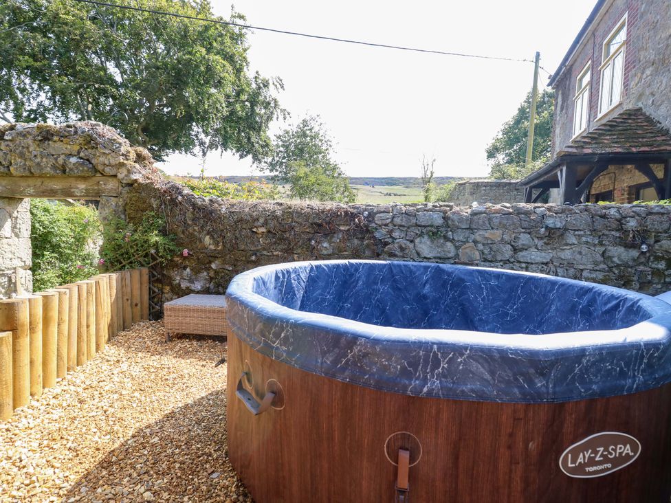 An outdoor area with a hot tub near a stone wall at Glebe Garth in Chale near Niton