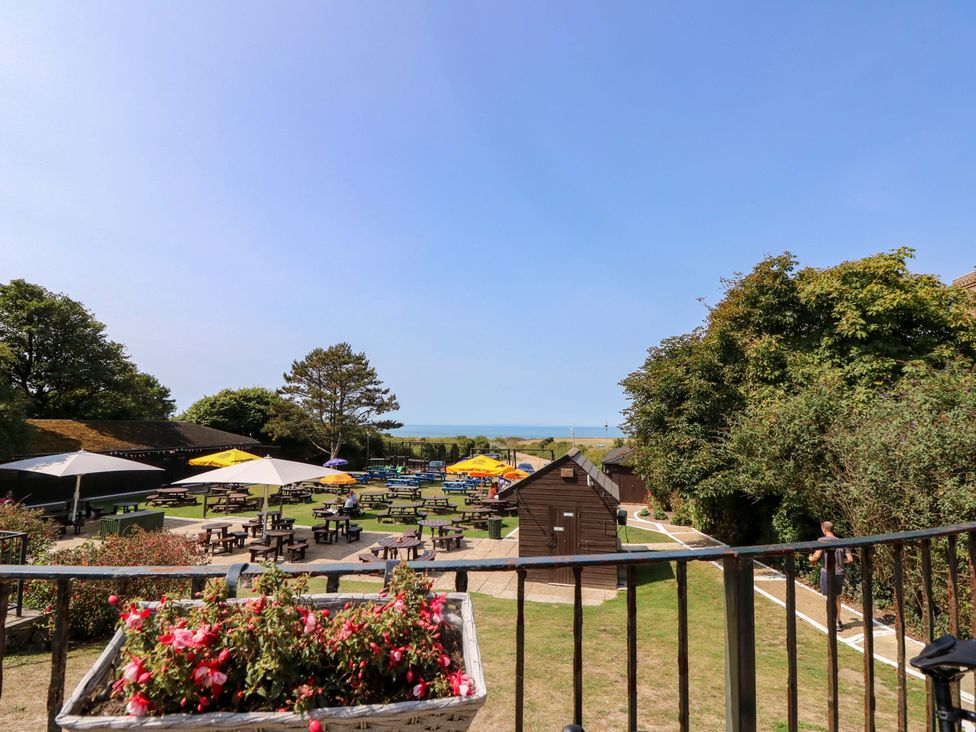 An outdoor area with benches and umbrellas at Glebe Garth in Chale near Niton