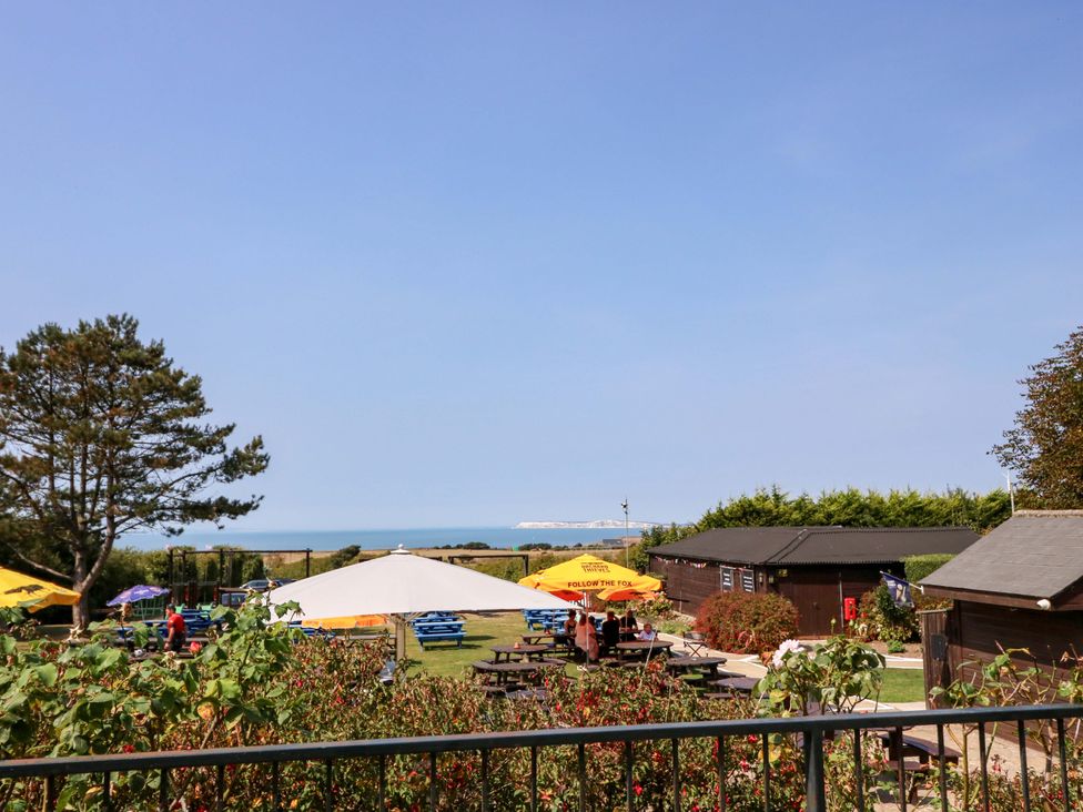 An outdoor area with picnic tables and umbrellas at Glebe Garth in Chale near Niton