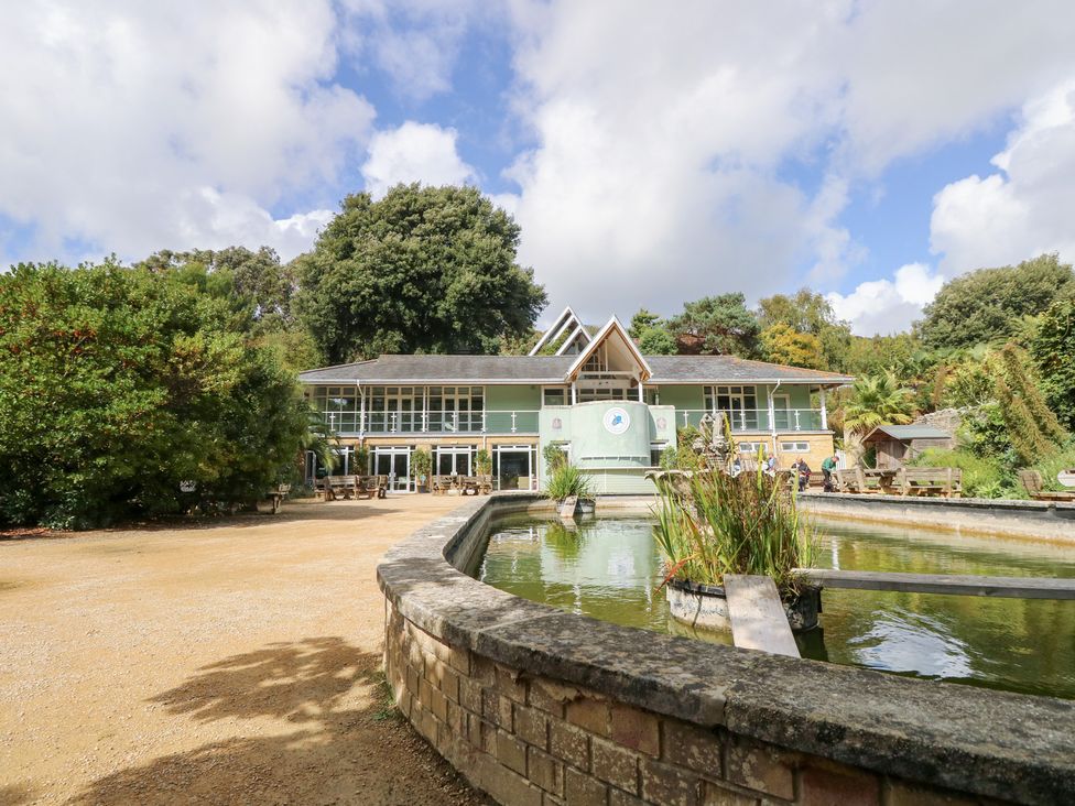 A building near a pond with trees and benches at Glebe Garth in Chale near Niton