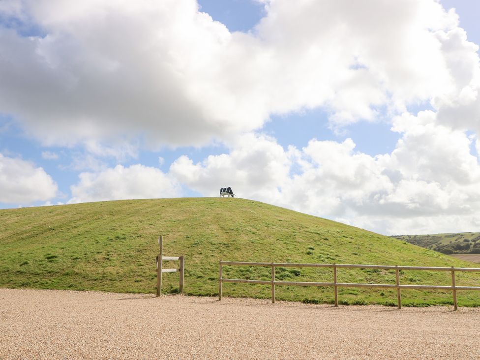 A grassy hill with a fence and a sign at Glebe Garth in Chale near Niton