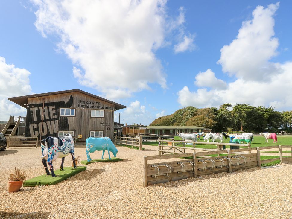 An outdoor view of a restaurant with decorative cows at Glebe Garth in Chale near Niton