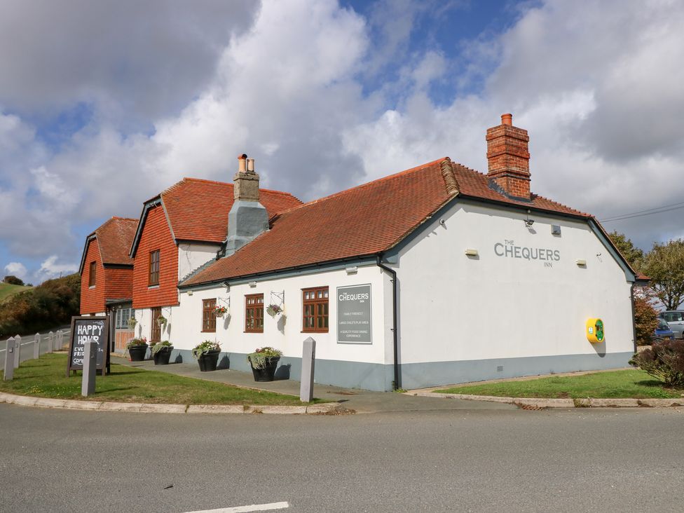 A pub building with a sign and planters at The Chequers Inn in Chale near Niton