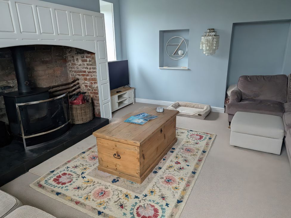 A living room with a fireplace, coffee table, and sofa at Glebe Garth in Chale near Niton