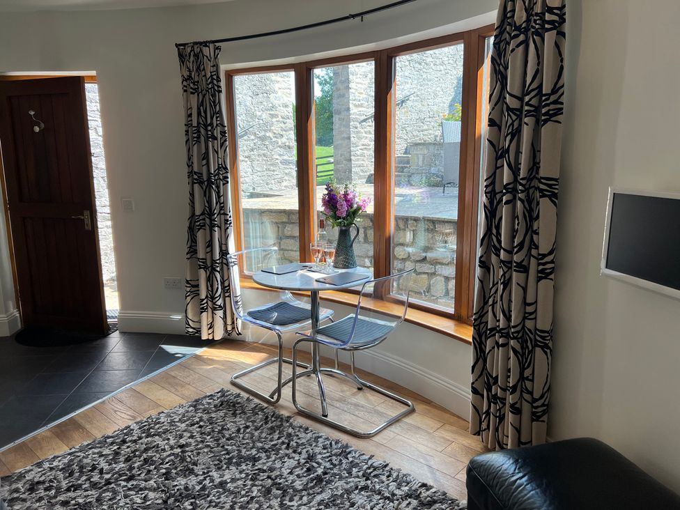 A dining area with a table and chairs near a window at Poppy's Footprint in Leyburn