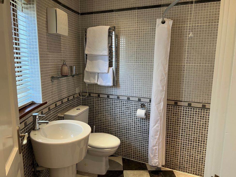 A bathroom with a sink, toilet, and shower at Poppy's Footprint in Leyburn