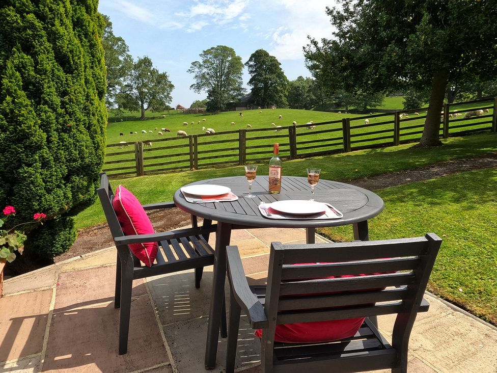 An outdoor seating area with a table and chairs at Poppy's Footprint in Leyburn