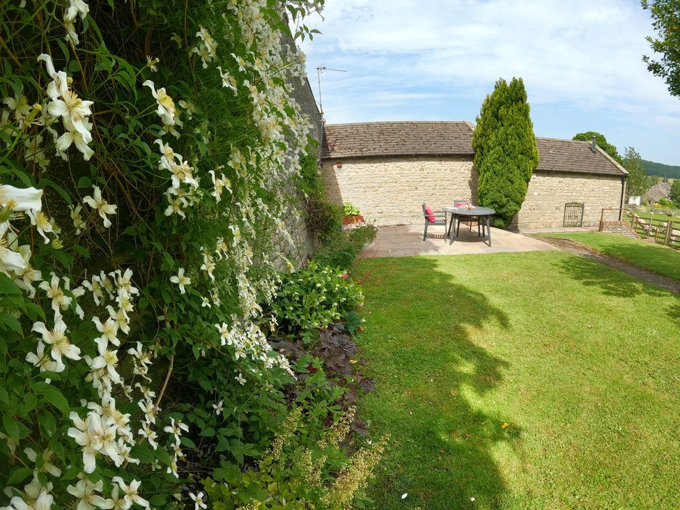 A garden with a stone wall and a table set at Poppy's Footprint in Leyburn