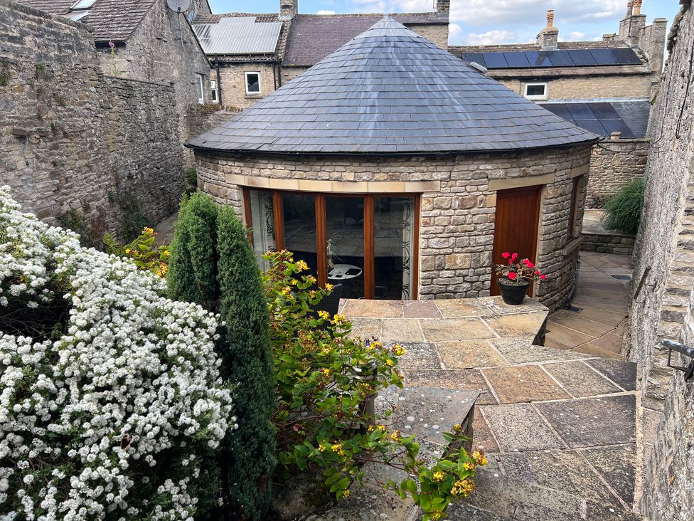 An outdoor area with a circular stone building and plants at Poppy's Footprint Leyburn