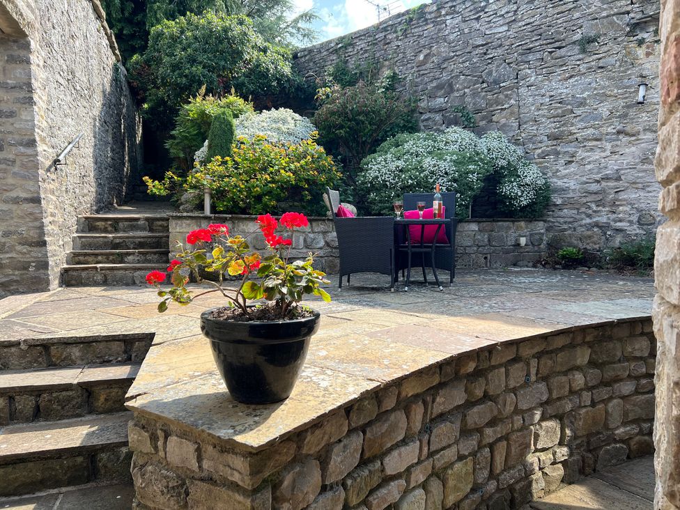 A garden with a potted plant and outdoor seating at Poppy's Footprint in Leyburn
