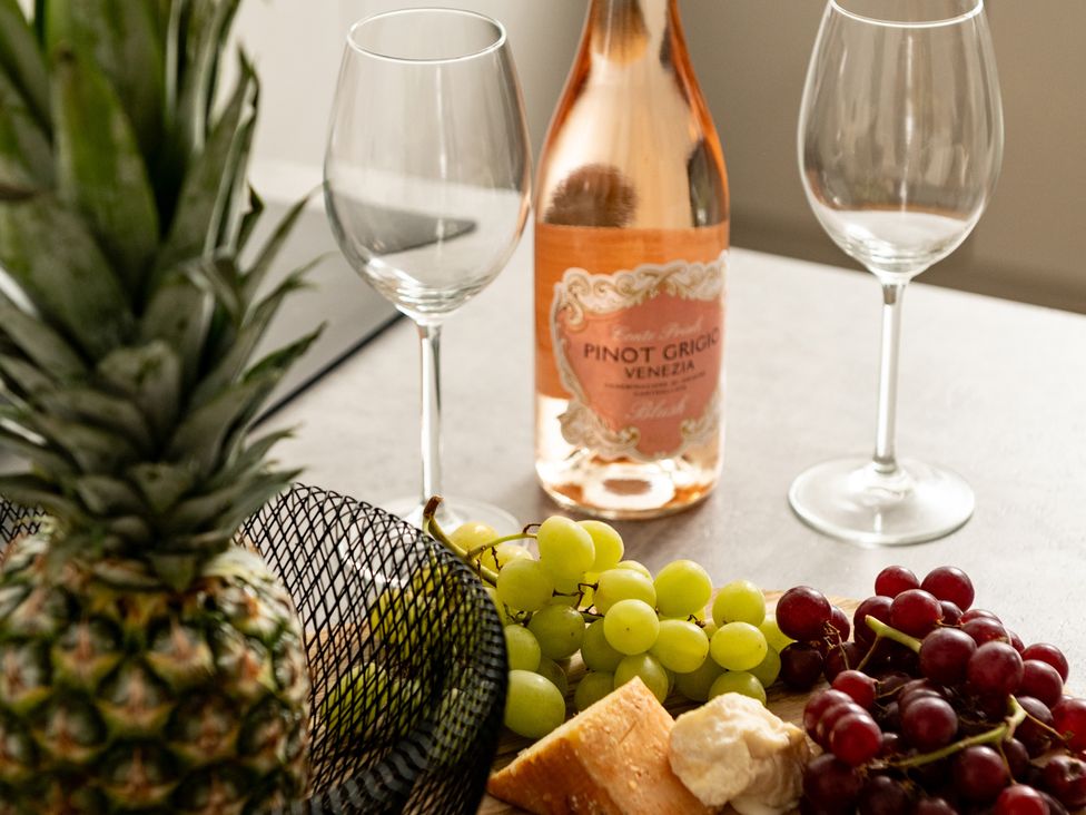 A table with pineapple, wine glasses, wine bottle, grapes, and cheese at Seaheaven