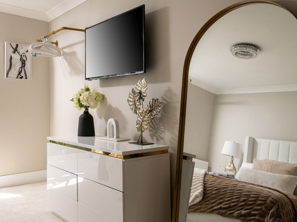 A bedroom with a television, dresser, and decorative plant at Seaheaven