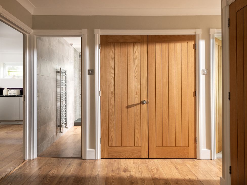 A hallway with double wooden doors and a wall leading to a bathroom at Seaheaven