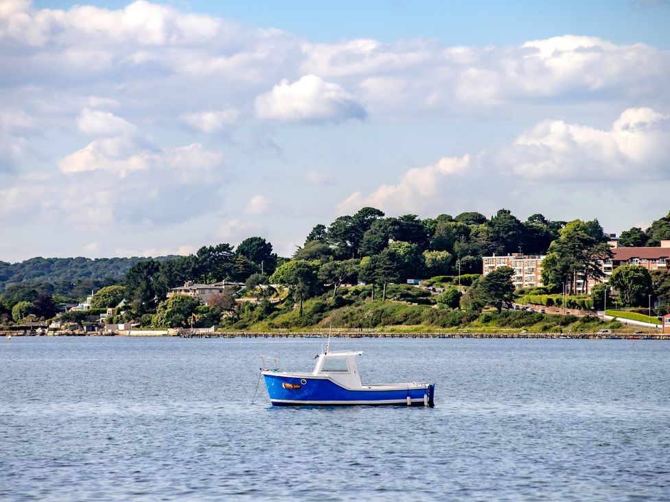 A blue boat on water with trees and buildings in the background at Seaheaven