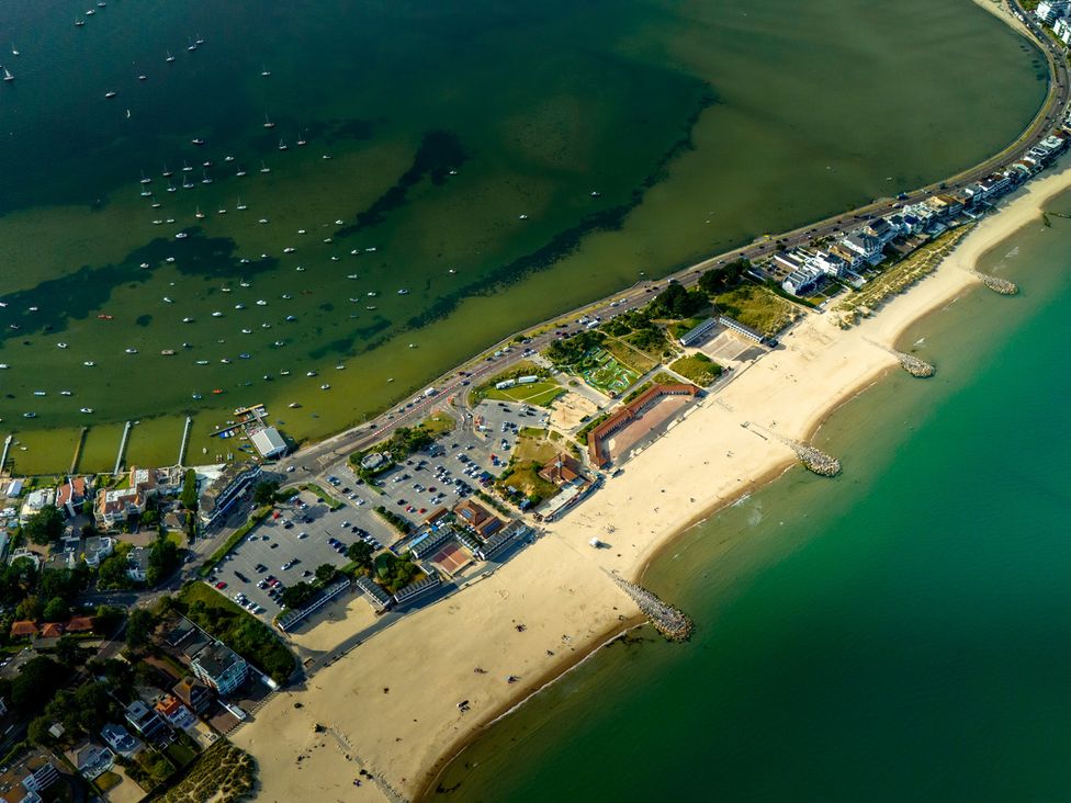 An aerial view of a beach and marina with parked cars and nearby buildings at Seaheaven